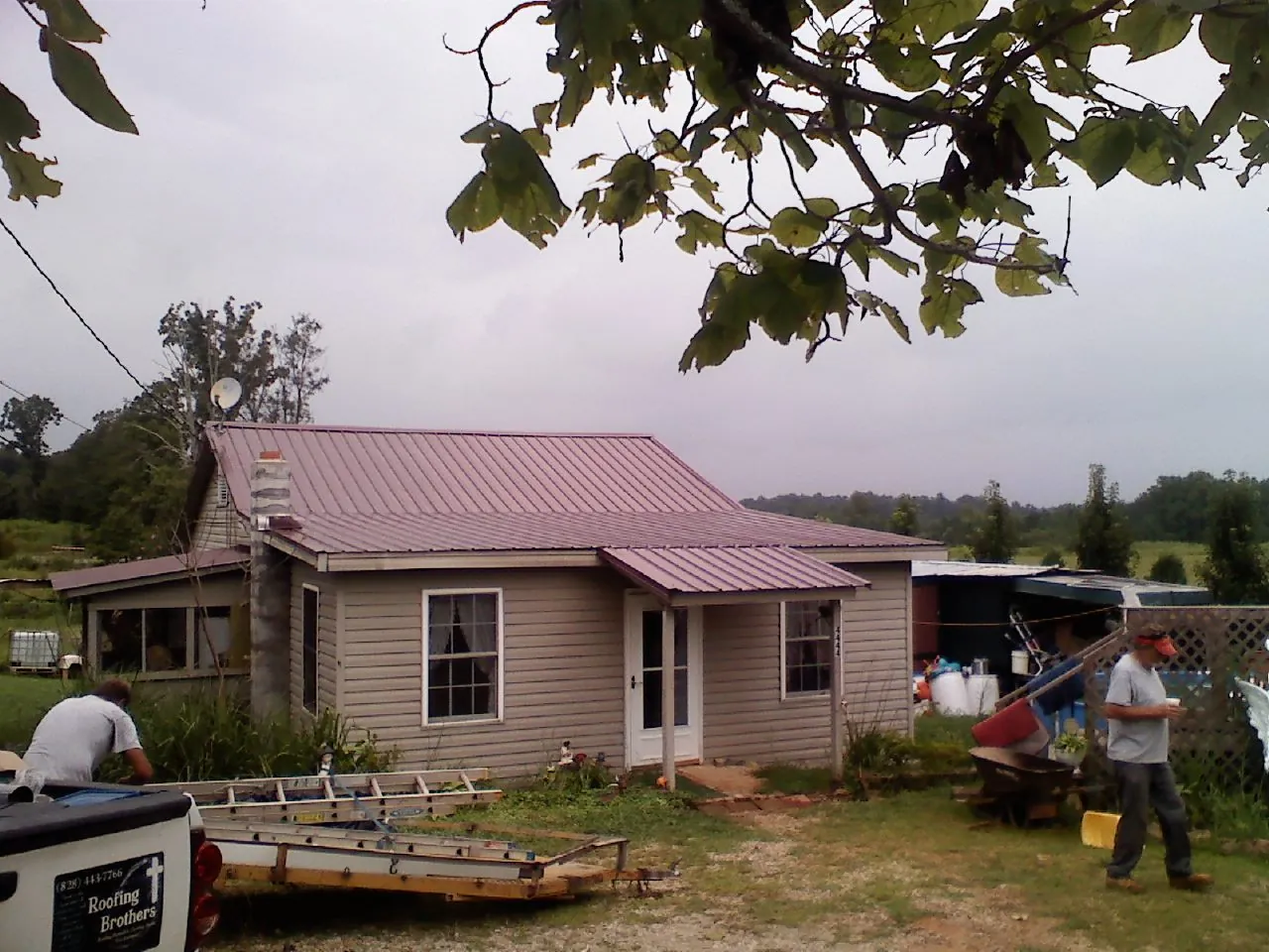 Crew finishing a mauve metal roof on a small farmhouse in Lewisburg